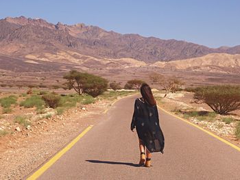 Rear view of woman on road against mountain