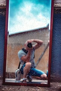 Full length of woman photographing through glass window