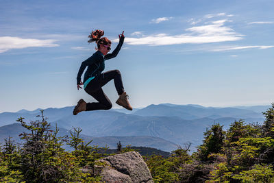 Man jumping in mountains against sky