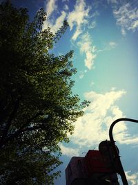 Low angle view of trees against cloudy sky