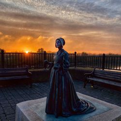 Full length of woman with cross against sky during sunset