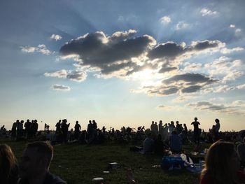 People on landscape against cloudy sky