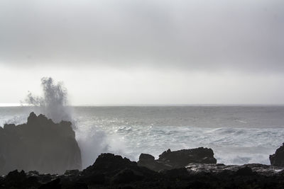 Waves crashing against black volcanic rock formations