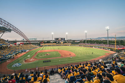 People watching baseball match against sky