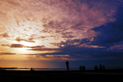 Silhouette people on beach against sky during sunset