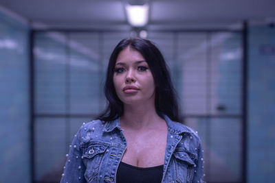 Portrait of fashionable young woman standing in illuminated built structure