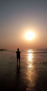 Silhouette man standing on beach against sky during sunset