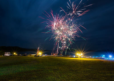 Firework display over field at night