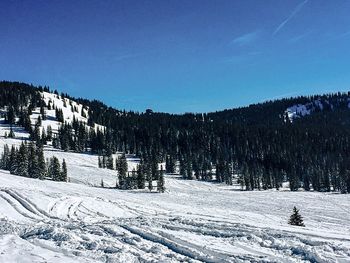 Scenic view of snow covered mountains against blue sky