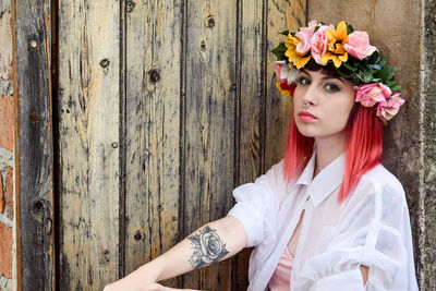 Portrait of young woman standing against wall