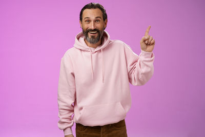 Midsection of man holding umbrella against pink background