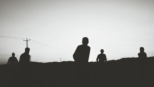 Silhouette people on landscape against clear sky