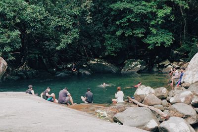 Group of people sitting on rocks by trees