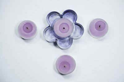 Directly above shot of purple tea light candles over white background