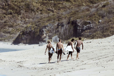 Unrecognizable surfers walking towards cliff