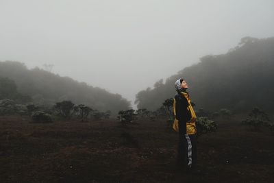 Woman standing on land during foggy weather