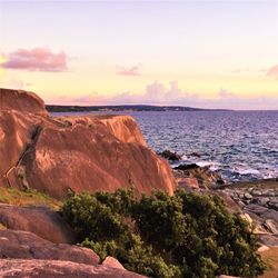 Rocks on beach against sky during sunset