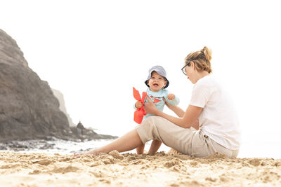 Rear view of woman sitting on sand at beach