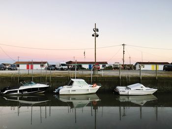 Boats moored at harbor against sky during sunset