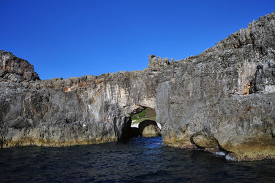 Scenic view of cliff against clear blue sky