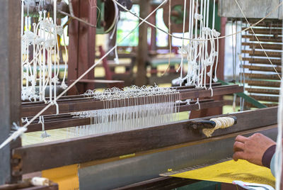 Cropped hand of person working on loom in factory