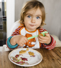 Portrait of cute girl eating food at home