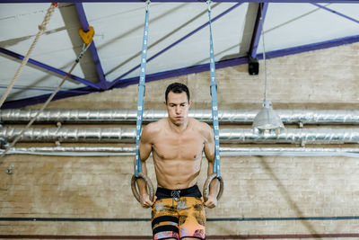 Male athlete with gymnastic rings doing exercise at gym