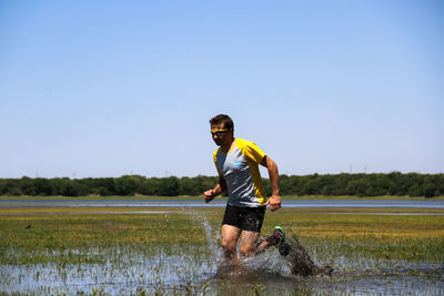 Full length of young man in lake against clear sky