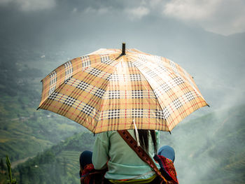 Full person with umbrella against mountains in vietnam