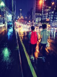 Rear view of women walking on illuminated street at night