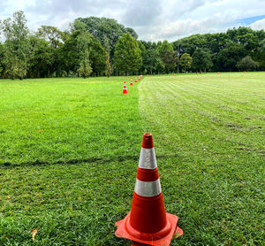 Signal cone on field by trees against sky