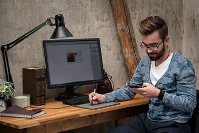 Side view of man using laptop while sitting on table