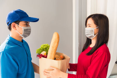 Smiling woman wearing mask taking delivery outdoors