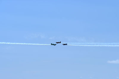 Low angle view of airplanes flying against blue sky