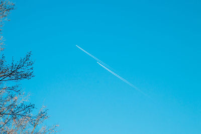 Low angle view of vapor trail against clear blue sky