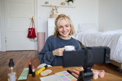 Portrait of young woman using mobile phone while sitting at home