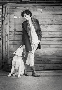 Full length of woman with dog on wooden floor