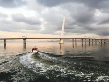 Bridge over sea against cloudy sky