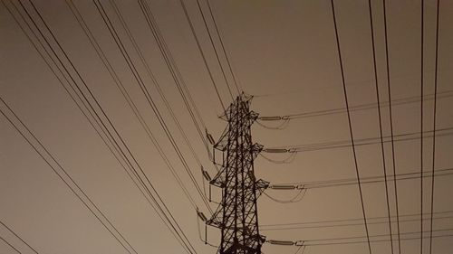 Low angle view of electricity pylon against sky at dusk