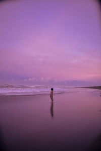 Man standing on beach against sky during sunset