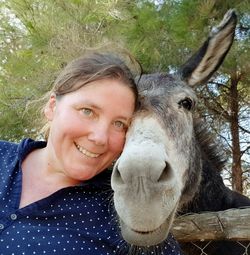 Portrait of smiling young woman outdoors with donkey