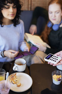 Young woman paying with card in cafe