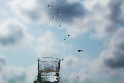Low angle view of glass of water against sky