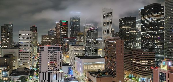 Illuminated buildings in city against sky