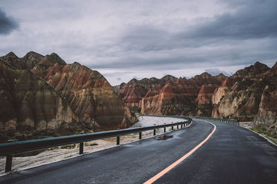 Road leading towards mountains against sky