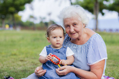 Portrait of grandmother sitting with granddaughter at park