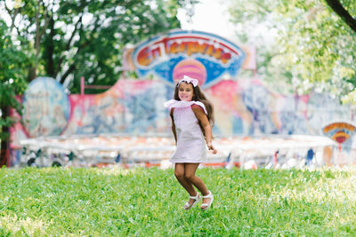 Cute little girl in the park jumping up on the grass and having fun