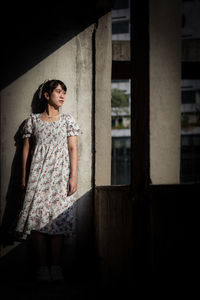 Young woman standing against wall