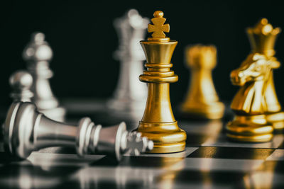 Close-up of chess pieces on board against black background