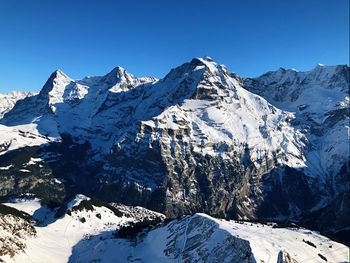 Scenic view of snowcapped mountains against clear blue sky